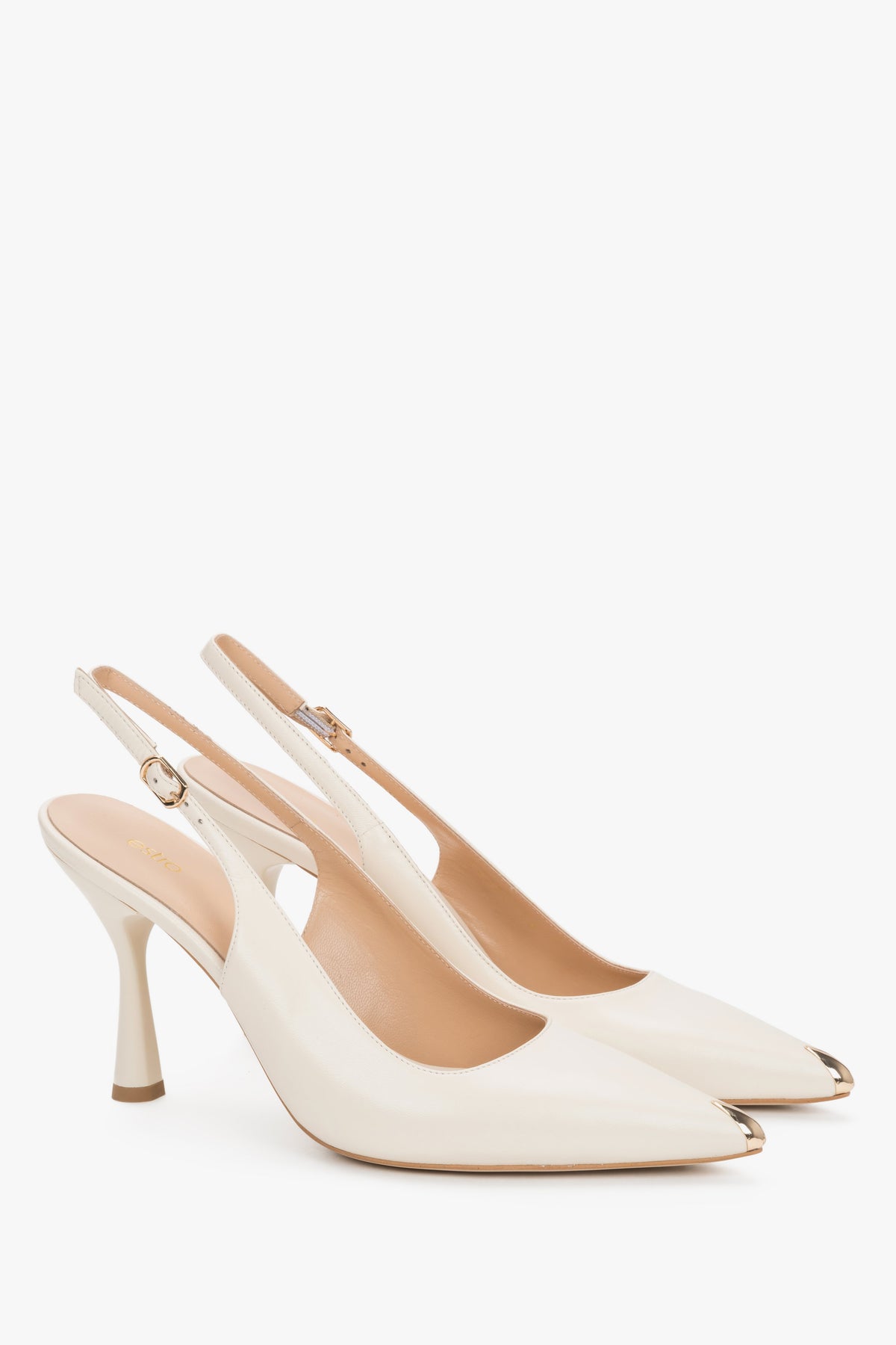 Jasnobeżowe czółenka slingback Estro na efektownym obcasie kielichowym, eksponujące otwartą piętę z paskiem oraz błyszczący, złoty szpic buta.